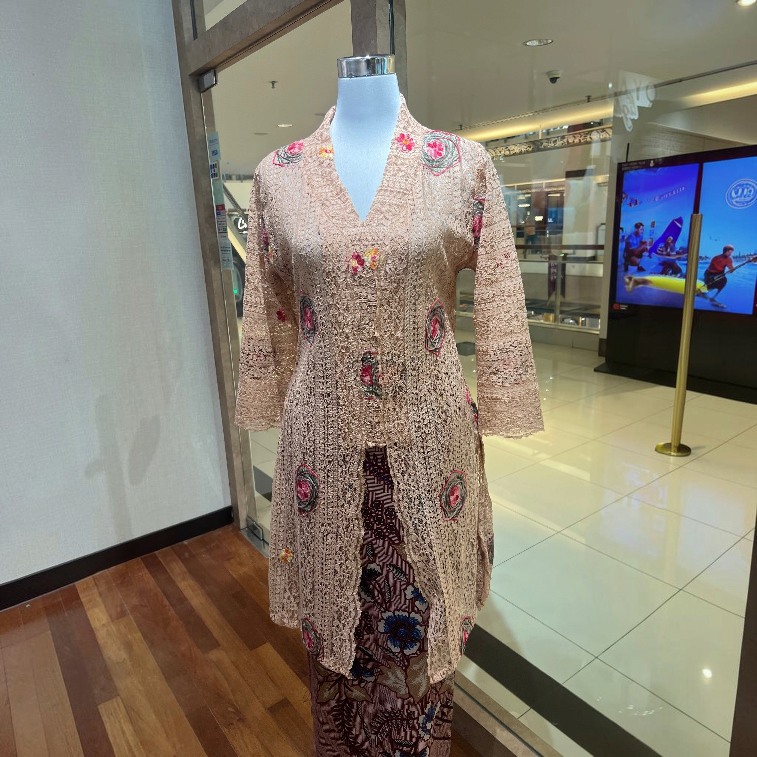 POYA brown long kebaya top in embroidered lace with floral patterns on a mannequin in a retail store setting